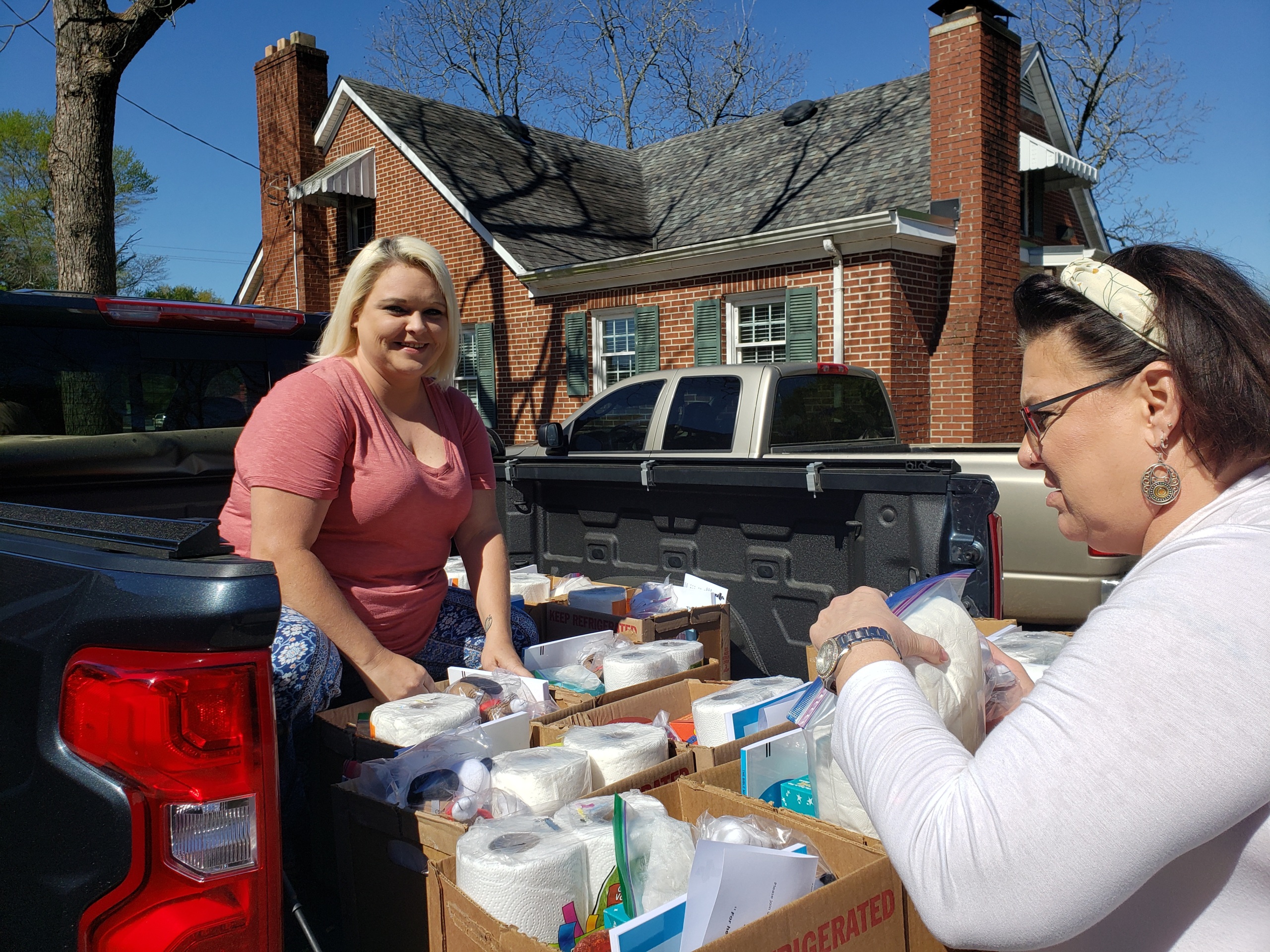 Two direct support professionals distributing meal kits out of the back of a pickup truck at the beginning of COVID-19